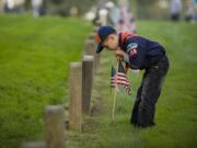 Grayson Much, 6, from Pack 359 in Hockinson, plants a flag at the Post Cemetery, Thursday, in preparation for the annual Veterans Day ceremony on Friday.