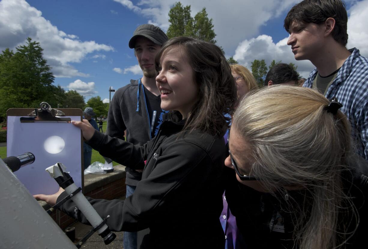 Michelle Pitel, 20, who is a student of Clark College astronomy and science teacher Dick Shamrell, holds a clipboard with an image of the sun projected onto it as Venus passes across the sun's face Tuesday.