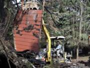 An excavator Monday morning removes burned debris from Steven Stanbary's property on F Place in Washougal. Stanbary killed himself, his wife and her twin sister Dec.