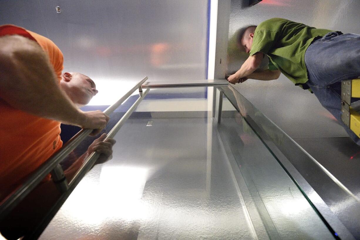 Jeremy Blakely, left, and Ryan Zaccheo, commercial glaziers for D&amp;L Glass, install a half-inch glass door at the new Cinetopia theater in Vancouver.