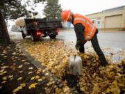 Bill Lamkin, part of the city of Vancouver's stormwater management team, clears leaves from a drain at the intersection of East 15th Street and Broadway in this file photo.