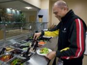 Jose &quot;Joe&quot; Red, 65, makes a salad for lunch on Wednesday while taking a break from his job as lead cashier in the Legacy Salmon Creek Medical Center cafeteria.