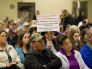 A property owner holds a sign criticizing one of several possible 500-kilovolt power line routes being considered by the Bonneville Power Administration during a listening forum at the Battle Ground Community Center on Dec.