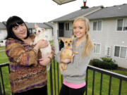 Michelle McLaughlin, left, with Lucky, stands with her daughter, Cora Hall, with Riley, on the balcony of their Orchards-area apartment.