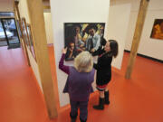 Diana Faville, left, and Maria Gonser hang a work by Sandra Jones Campbell at the Attic Gallery&#039;s new location in Camas.