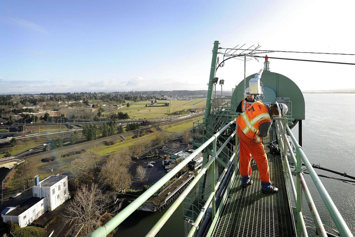 Oregon Department of Transportation bridge supervisor Marc Gross, foreground, and Ryan Cox, assistant supervisor, install a propane-powered air cannon on the Interstate Bridge on Thursday.