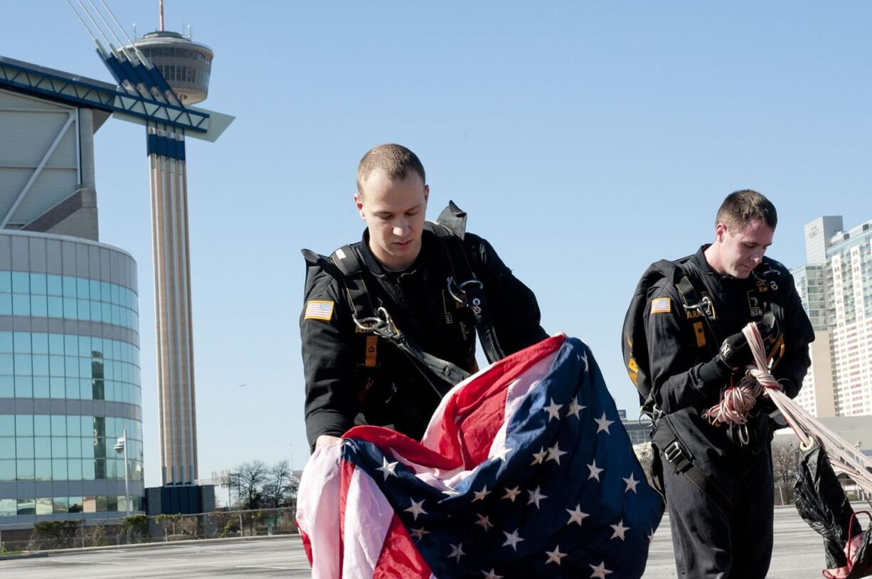 Sgt. Alex Bahry, left, and Sgt. 1st Class Brian Karst of Vancouver gather their parachutes and an American flag after a 6,000-foot jump last week in San Antonio. They were part of the weeklong activities at the 2016 Army All-American Bowl high school all-star football game. (Sgt. Brandon Hubbard/U.S.