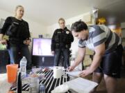 Community corrections officers Beth Graves, left, and Jennifer Thomas watch as offender Jason Wilen signs a document in his home earlier this month acknowledging a new &quot;swift and certain&quot; law for offenders.