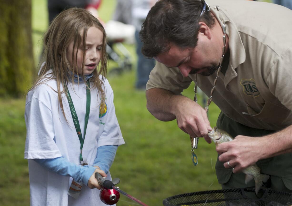 Steven Lane/The Columbian
Ken Sandusky, with the U.S. Forest Service, removes the hook from Kindell Frampton's first trout, which she caught in the fishing pond at the Get Outdoors Day event at the Fort Vancouver National Site on Saturday. The two fishing ponds were stocked with 800 trout.