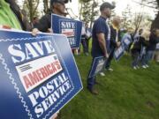 Letter carriers and members of the public hold signs on Thursday on Officers Row during a demonstration to protest changes to the U.S.