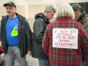 A pro-terminal supporter walks past Edie Cotton, left, who had a sign on her back opposing the terminal, as they attended the Energy Facility Site Evaluation Council&#039;s hearing Jan. 12 in Ridgefield on the construction of an oil terminal in Vancouver.