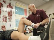 Dr. Kevin deWeber examines the knee of an injured soccer player Thursday at Clark College&#039;s O&#039;Connell Sports Complex. DeWeber is a sports medicine physician and, this summer, will be the medical director of the High Performance Center at the Rio 2016 Olympics.