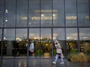 A woman tries to shield herself from the rain and wind as she walks toward the front doors of the Vancouver Community Library on Wednesday.