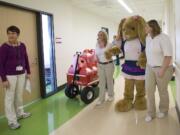 Certified child life specialist Susan Gallegos, from left, looks down the hospital corridor as Build-A-Bear employees Darcy Potter and Shannon Nashis help guide Danielle Thomas, who is dressed in a bunny suit, while visiting patients.