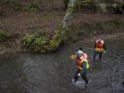 Ian Wigger, left, a Clark County natural resource specialist, and Kevin Gray, the county's director of Environmental Services, take measurements in Mill Creek near Washington State University Vancouver last month. At stream monitoring stations, a cable runs down to the water to measure depth and velocity. The data can be downloaded to computers or smartphones. To verify accuracy, however, the sites are periodically checked the old-fashioned way. The flags on the bank mark plantings of native vegetation done by Clark Public Utilities. Both the monitoring and plantings illustrate efforts to comply with rules regarding clean water.