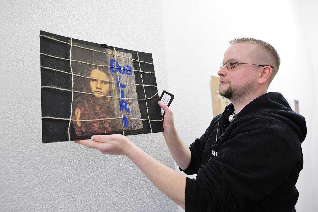 Drew Parsons hangs a mixed media art piece by a high school art student from Gjilan, Kosovo that shows a girl confined behind a grid with the caption &quot;I want freedom.&quot; &quot;This is one of the more powerful pieces,&quot; said Parsons.