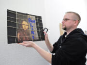 Drew Parsons hangs a mixed media art piece by a high school art student from Gjilan, Kosovo that shows a girl confined behind a grid with the caption &quot;I want freedom.&quot; &quot;This is one of the more powerful pieces,&quot; said Parsons.