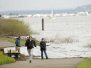 The Columbia River swallows up part of the Waterfront Renaissance Trail as Dave Altman, center, of Vancouver and Greg and Cheryl Fewins of Puyallup navigate around the flooded path on Sunday.