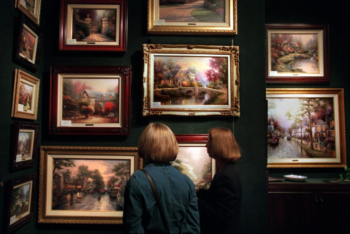 Customer Jennifer Foster, left, and gallery director Tina Grimes survey Thomas Kinkade's work at the Weir's Furniture Village in Plano, Texas, in this Dec. 18, 2000 file photo.  To his legions of fans, a mere look at Kinkade's work draws them into its settings.