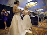 Models, from rear left, Gina Perrone, 28, of Portland; Lacey Koplan, 28, of Vancouver; and makeup artist and model Kendal Moore, 22, of Vancouver, work the booth for AJ's Hair and Makeup at the Marry Me!