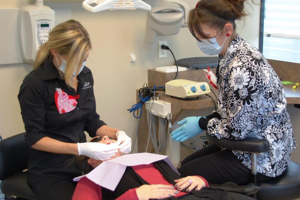 Sarah Barber, left, of Smiles Dental works on a patient alongside dental assistant Linda Heilmann during Doctor With a Heart Day on Feb.