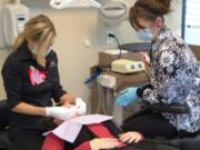 Sarah Barber, left, of Smiles Dental works on a patient alongside dental assistant Linda Heilmann during Doctor With a Heart Day on Feb.