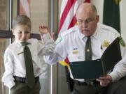 Carter Harris, 4, takes the oath of office from Clark County Sheriff Garry Lucas as he is named sheriff for a day on Wednesday.