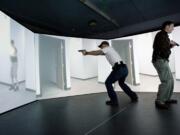 Photos by steven lane/The Columbian
Camas Police officers Henry Scott, left, and Tim Fellows deal with a gunfight  scenario Wednesday inside a five-screen,  300-degree training stage at Threat Dynamics in Tualatin, Ore.