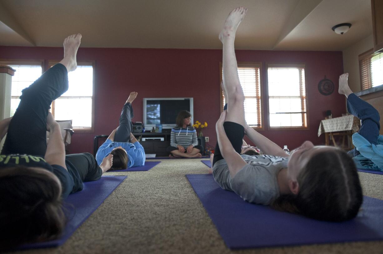 Julie Wiesner, background center, leads a group of girls through a recent Yoga Calm class at her home studio in Felida.