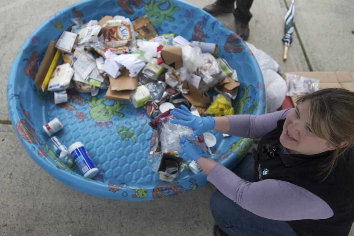 Terra Heilman, waste-reduction specialist with Waste Connections, explains which items are recyclable as she picks through the contents of a family's recycling bin Wednesday at the home of Tracy Davis.