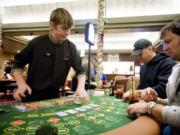 Kevin Hildebrandt, center, and Vaughn Kercher, both from Seattle, play poker at dealer Nate Wheatley's table at the Oak Tree Casino on Saturday, the Woodland card room's opening day.