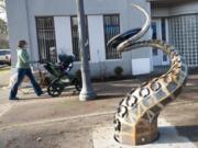 A woman pushes a stroller Wednesday past &quot;The Visitor,&quot; a new steel sculpture by Seattle artist Matthew Dockrey at West 23rd and Main streets.