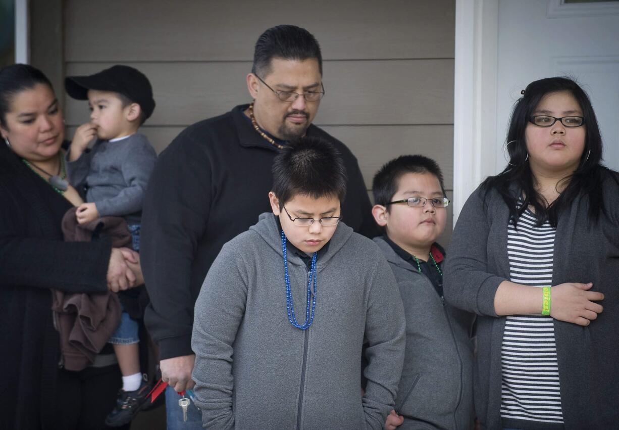 Lucrecia Tudela, left, and her husband, Cristino Cabrera, stand on the porch of their new home with their children (from left) Tyce, 2, Champ, 10, Ky, 7, and Ritaciah, 12, for a prayer at the dedication.