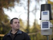 Tyler Mode shows off one of his two weather stations, which measures humidity, rain and temperature, at his parents' Vancouver home. Mode's other station is at his home in Battle Ground.