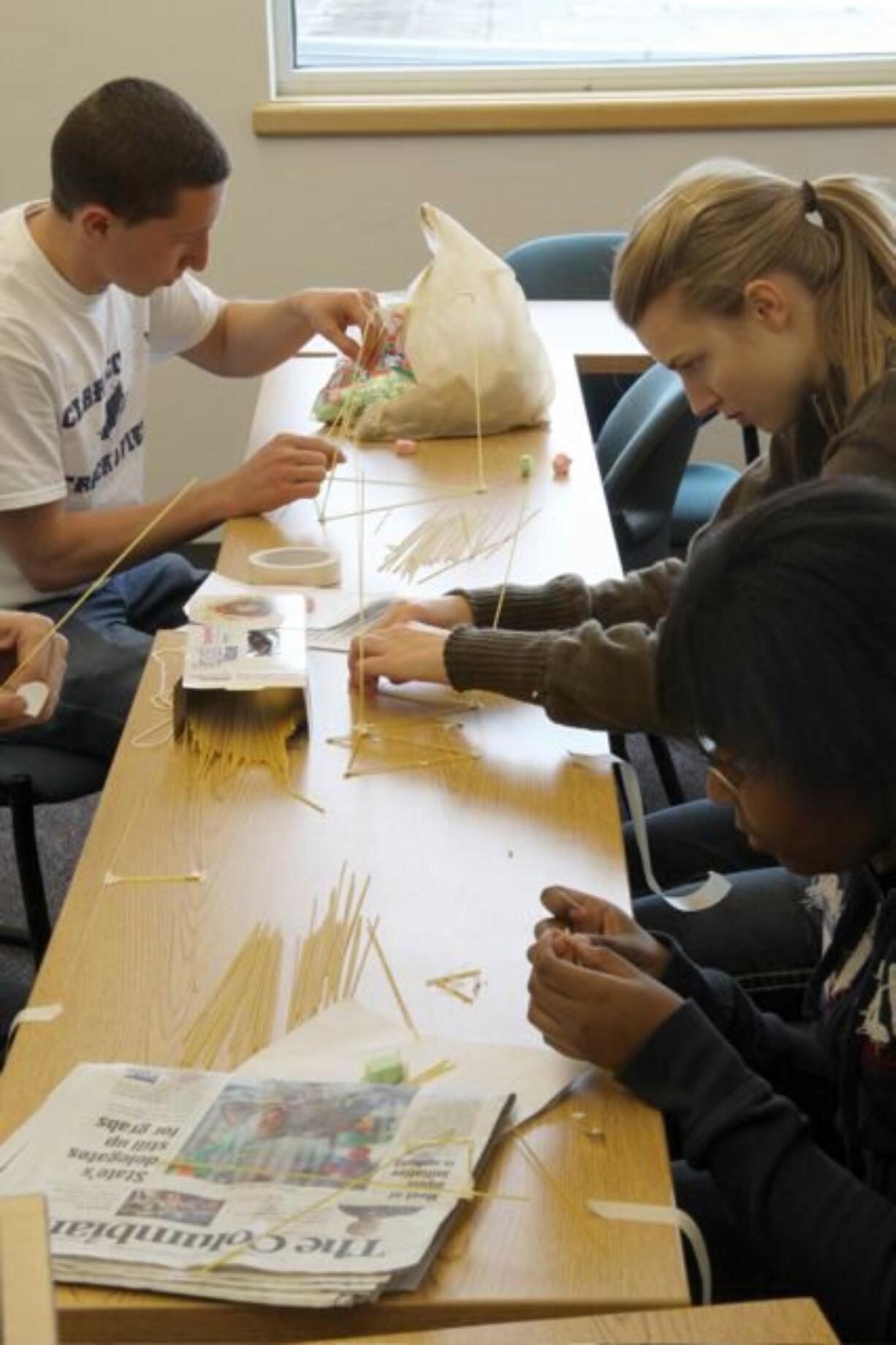 Central Park: Grace Nelson, Mary Huibregtse and Alin Resiya use uncooked spaghetti and tape to explore the best structural shape to support a weight-bearing load of marshmallows.