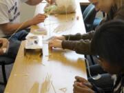 Central Park: Grace Nelson, Mary Huibregtse and Alin Resiya use uncooked spaghetti and tape to explore the best structural shape to support a weight-bearing load of marshmallows.