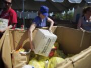 Volunteer Laura Fernandez helps unload canned goods from mail crates at the Caples Road post office during the 2012 letter carriers food drive.