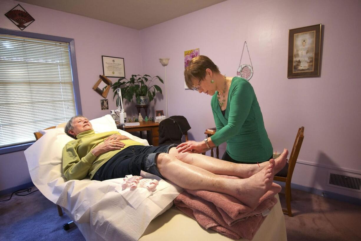 Jowanna Harman-Stever, right, of New Harmony Health in Vancouver, provides acupuncture treatment to patient Virginia Barber, 80, recently.