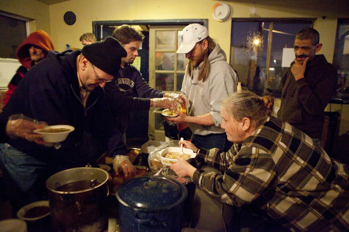 From left, Clark County residents John Buchanan and Josh Hutchinson, serve hot food to residents Scott Layman and Mary Turner at the Dignity Village community center in Portland.