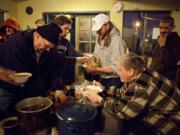 From left, Clark County residents John Buchanan and Josh Hutchinson, serve hot food to residents Scott Layman and Mary Turner at the Dignity Village community center in Portland.