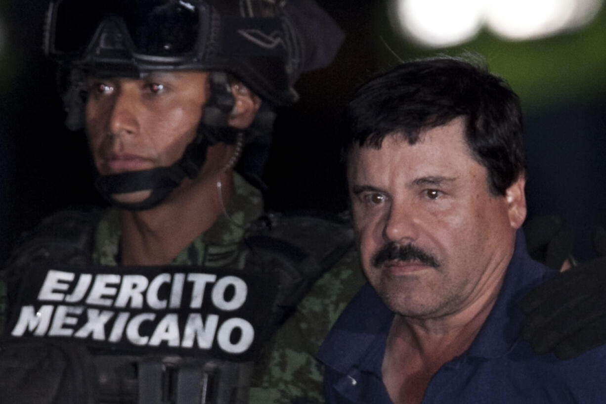 Mexican drug lord Joaquin &quot;El Chapo&quot; Guzman, right, is escorted by soldiers and marines to a waiting helicopter at a federal hangar in Mexico City on Friday.