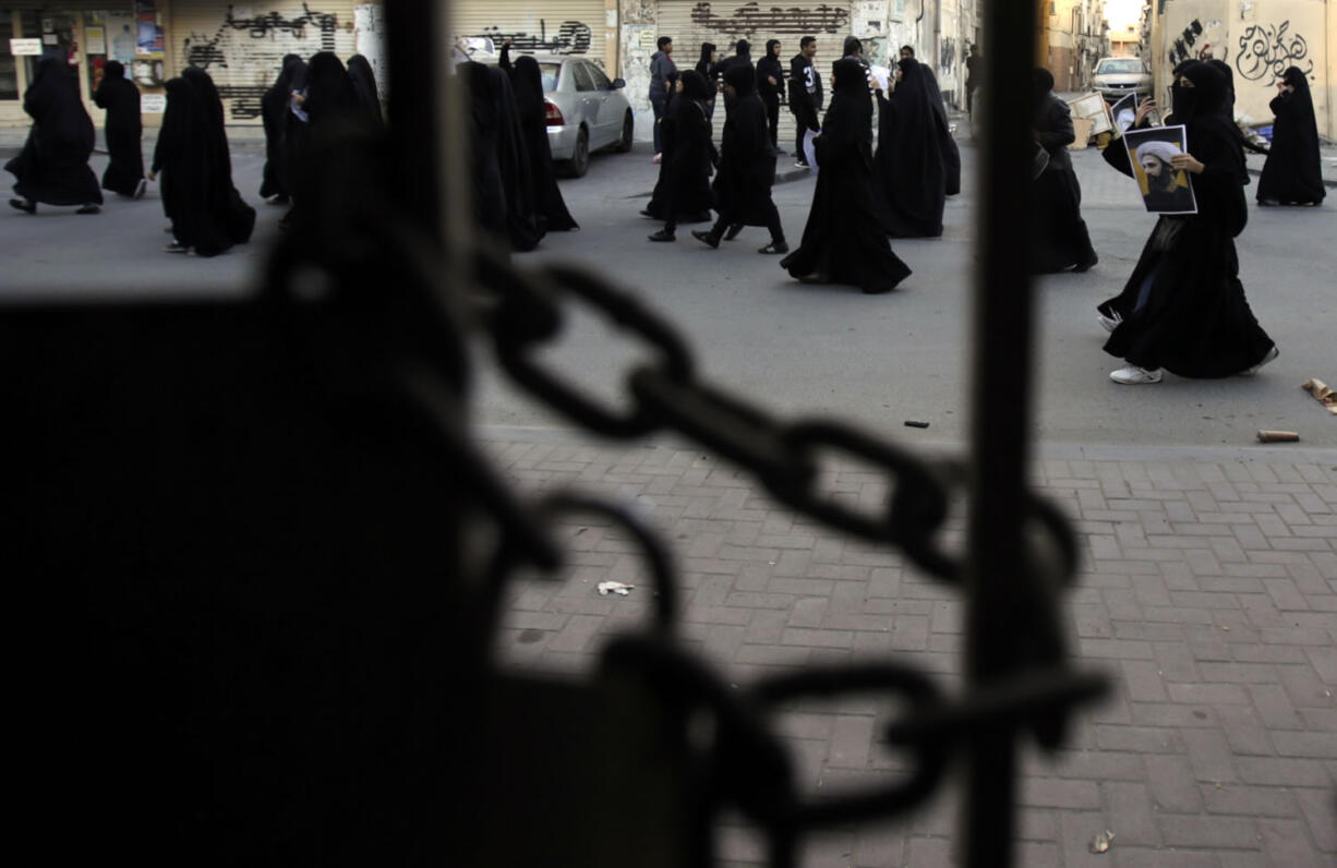 Bahraini protesters are seen through a locked gate as they carry pictures of Saudi Shiite cleric Sheikh Nimr al-Nimr during a demonstration against his execution by Saudi Arabia, Sunday, Jan. 3, 2016, in Daih, Bahrain. Saudi Arabia announced the execution of al-Nimr on Saturday along with 46 others. Al-Nimr was a central figure in protests by Saudi Arabia&#039;s Shiite minority until his arrest in 2012, and his execution drew condemnation from Shiites across the region.