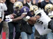 Washington's Kevin Smith (8) dives into the end zone on a 22-yard touchdown carry as Colorado's Tony Jones defends on in the first half Saturday.