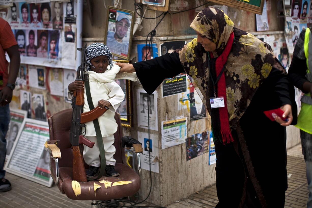 A young boy holds a weapon given to him by a rebel fighter as he poses for a portrait after Friday prayers in Benghazi, Libya.