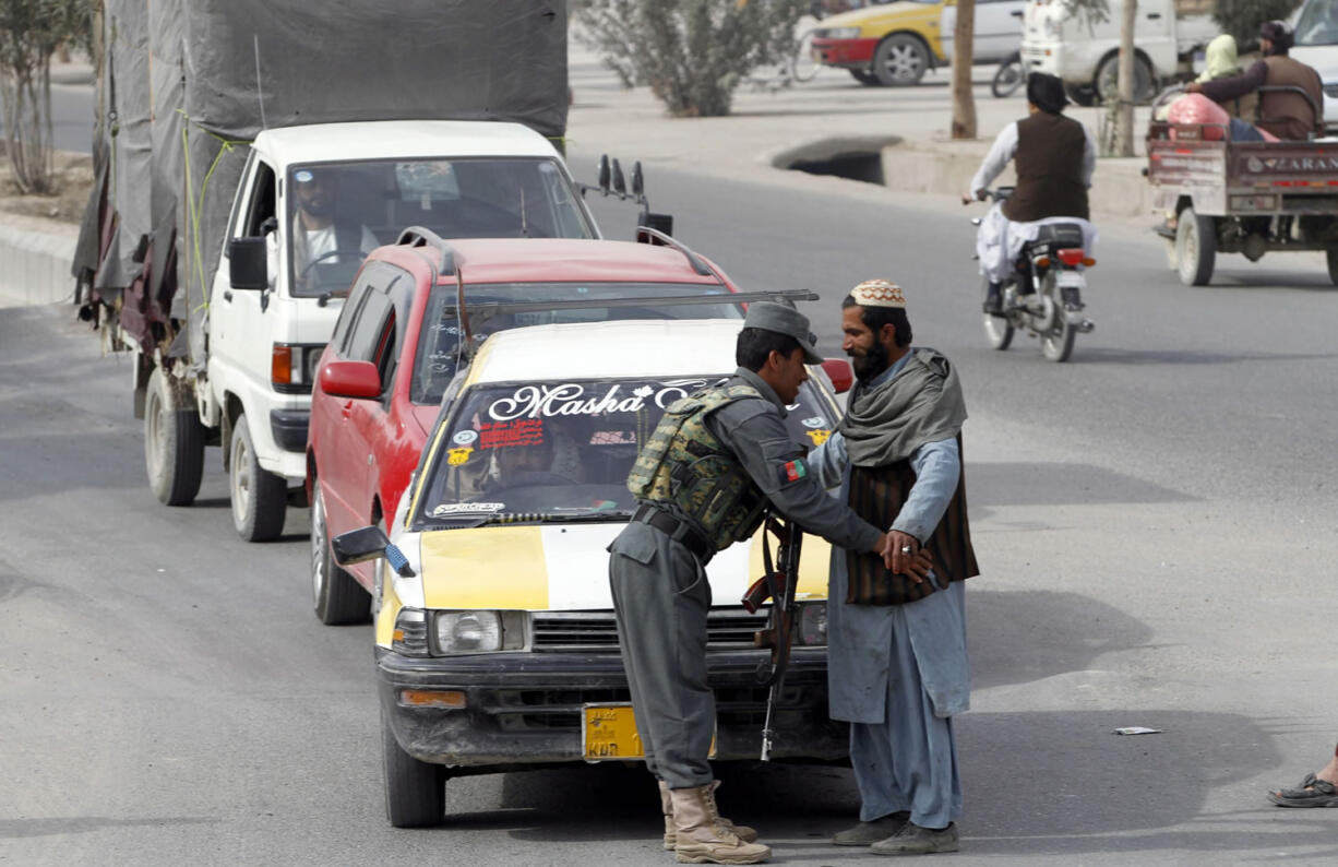 A policeman searches a passenger at a checkpoint Tuesday in Kandahar, Afghanistan. An Afghan official says that a policeman has turned his weapon on fellow officers at a checkpoint, killing 10.