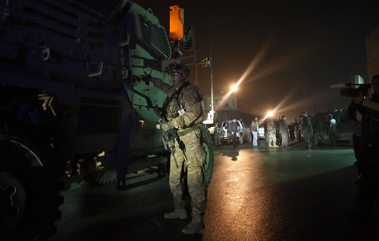 A U.S. soldier stands near his vehicle at the site of a suicide attack near a compound belonging to foreigners in Kabul, Afghanistan, on Monday. Afghan troops rappelled from helicopters onto the roof of a four-story building near the Indian Consulate in a northern city on Monday to drive out gunmen who had attacked the diplomatic mission the night before, officials said.