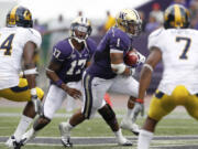 Washington quarterback Keith Price (17) yells after handing off to Chris Polk as California defenders Cecil Whiteside (14) and D.J.