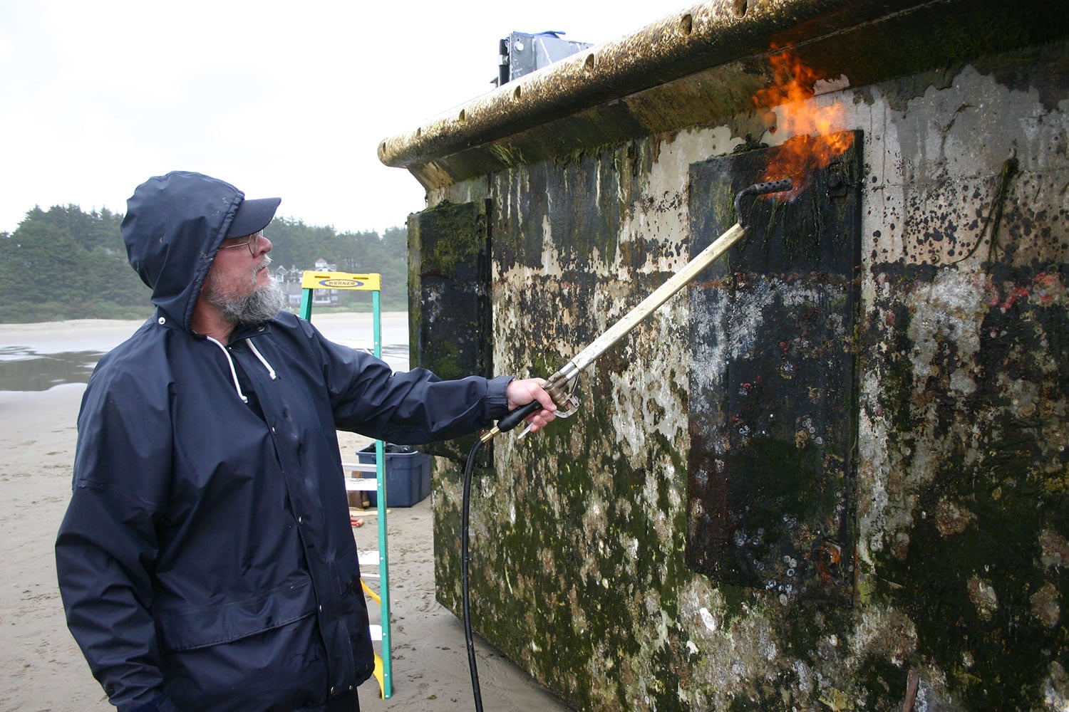 In this Thursday, June 7, 2012 photo proivded by the Oregon Park and Recreations Department, an unidentified worker burns off debris from a dock float torn loose from a Japanese fishing port by the 2011 tsunami that washed up Tuesday on Agate Beach near Newport, Ore.