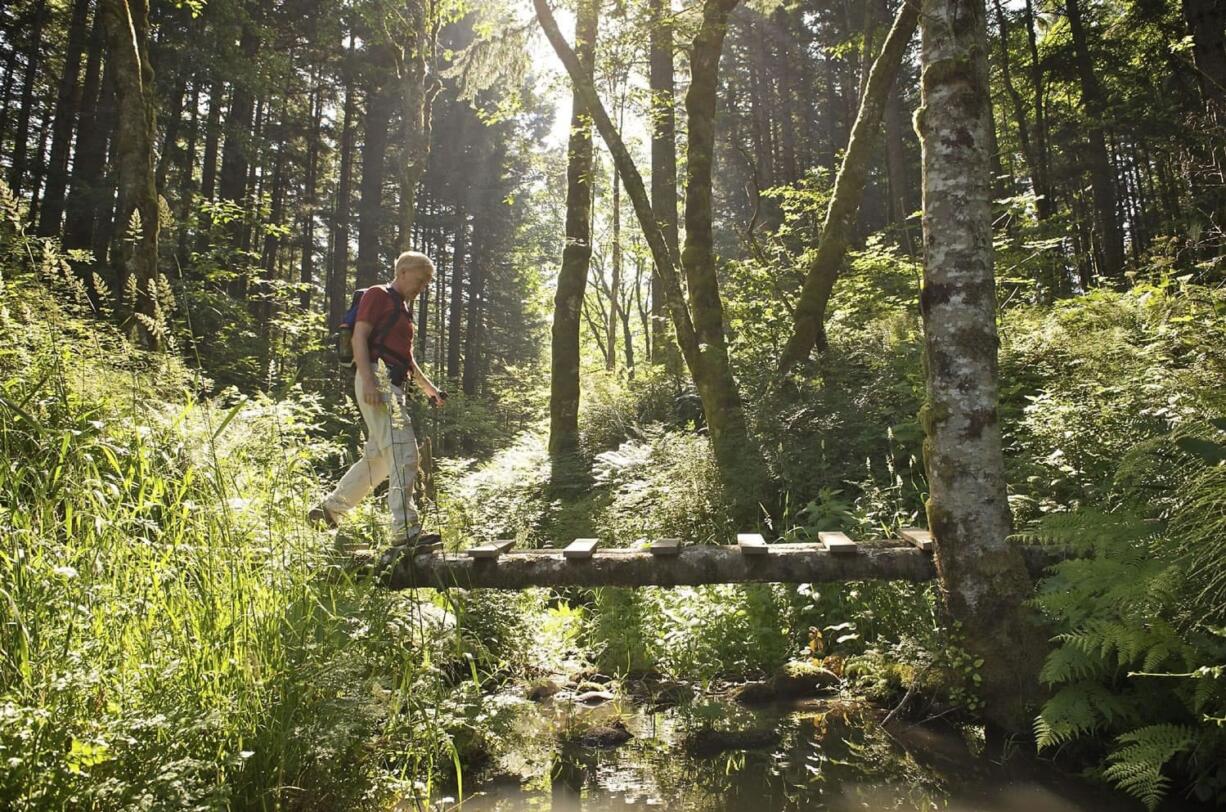 Don Nelsen of Vancouver crosses a makeshift bridge spanning the outlet creek of Carpenters Lake near North Bonneville.