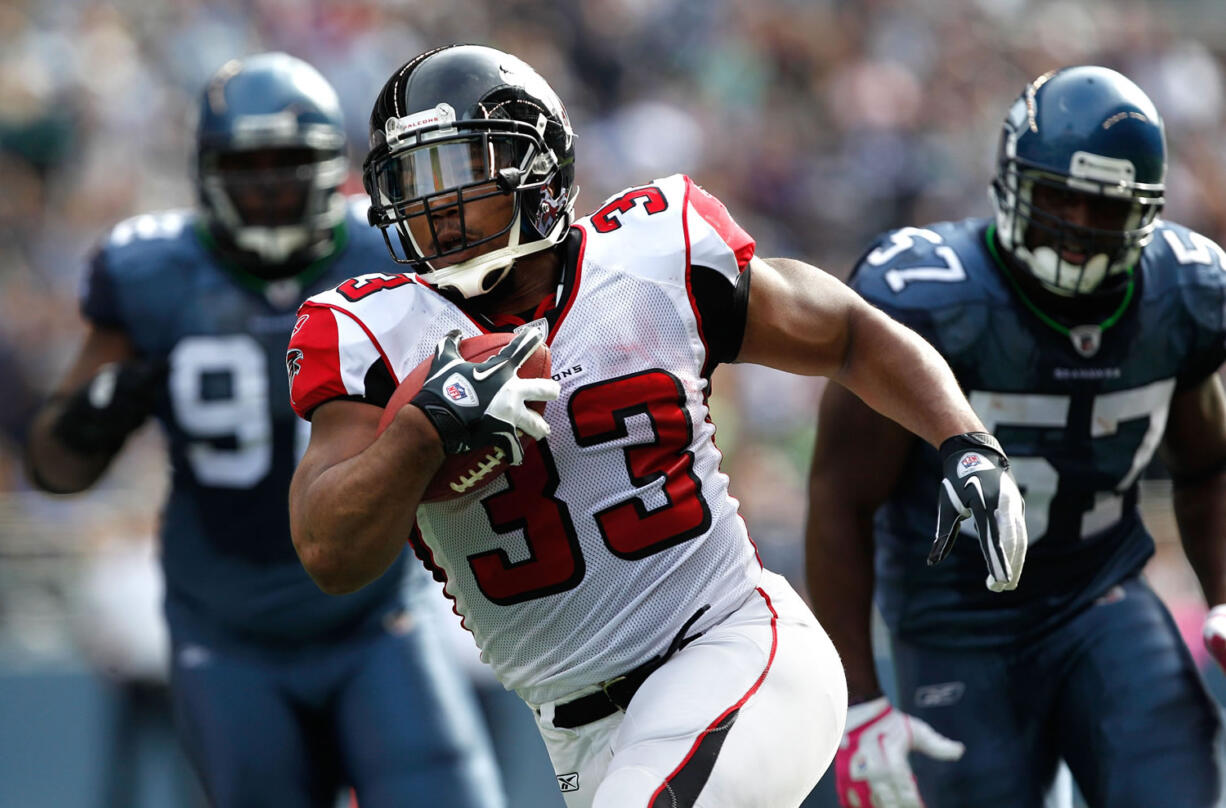 Atlanta Falcons Michael Turner (33) breaks away from Seattle Seahawks Brandon Mebane, left and David Hawthorne, right, to score a touchdown in the second quarter Sunday.